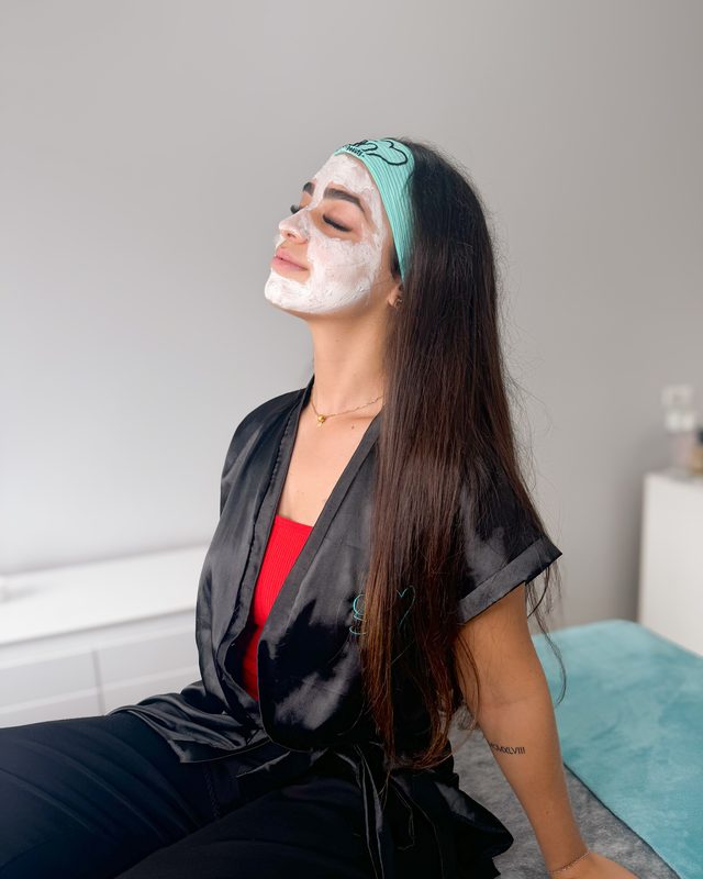 Cliente com máscara facial em cabine de estética.