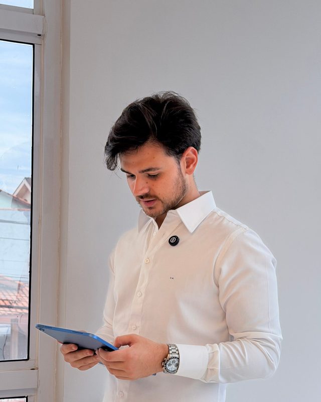Profissional de camisa branca consultando um tablet.