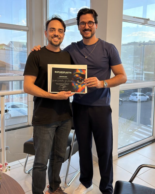 Aluno recebendo o certificado do curso de blefaroplastia ao lado do professor.