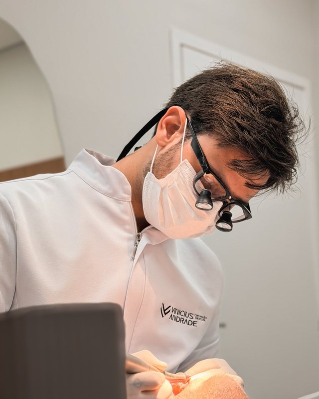 Dentista com lupa cirúrgica durante atendimento.